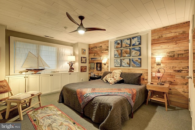 bedroom with ceiling fan, wooden walls, and carpet flooring