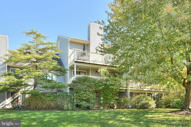 back of property featuring a balcony and a yard