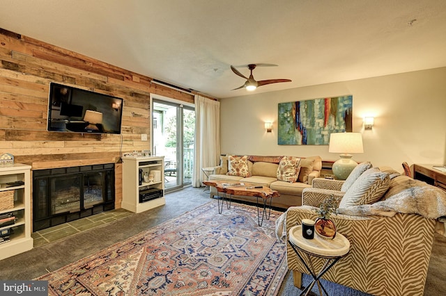 carpeted living room featuring wooden walls and ceiling fan