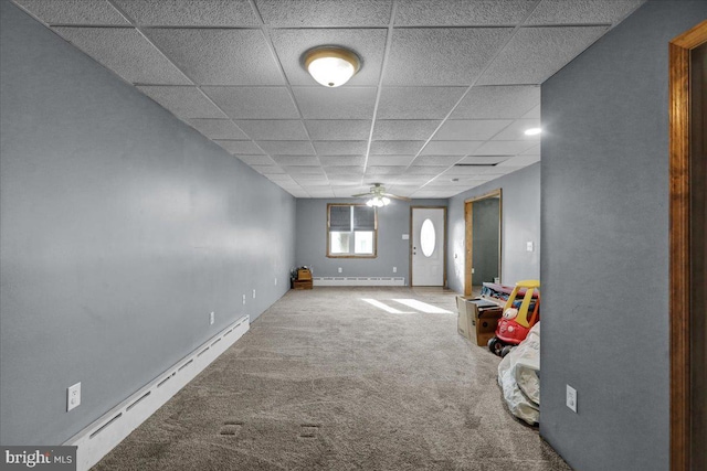 basement with a baseboard heating unit, carpet flooring, a paneled ceiling, and ceiling fan