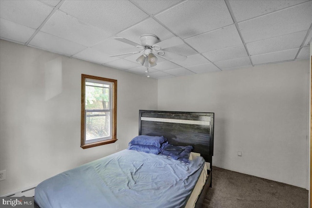 bedroom with ceiling fan, baseboard heating, a paneled ceiling, and dark colored carpet