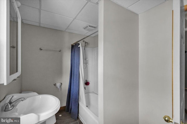 full bathroom featuring sink, hardwood / wood-style floors, shower / bath combination with curtain, a paneled ceiling, and toilet