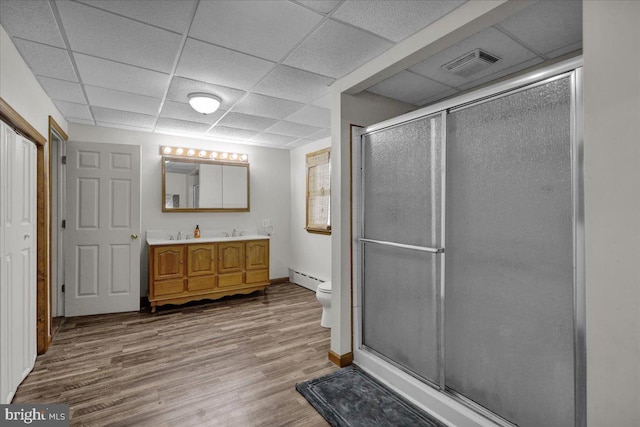 bathroom featuring a baseboard radiator, a shower with door, hardwood / wood-style flooring, toilet, and vanity