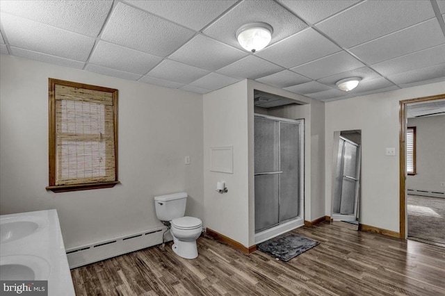 bathroom featuring baseboard heating, hardwood / wood-style floors, a shower with shower door, and toilet