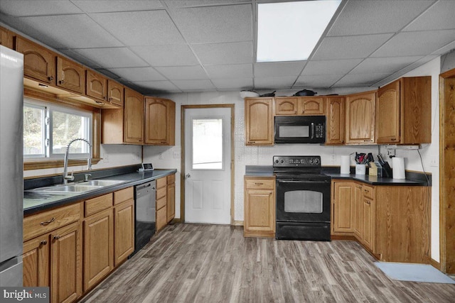 kitchen with light hardwood / wood-style flooring, black appliances, sink, and a drop ceiling