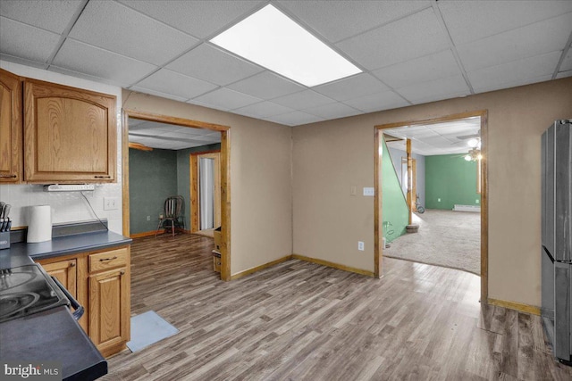 kitchen featuring a drop ceiling, light wood-type flooring, stainless steel fridge, ceiling fan, and stove