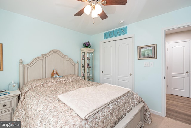 bedroom with light hardwood / wood-style flooring, ceiling fan, and a closet