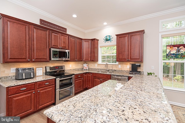 kitchen featuring plenty of natural light, light stone countertops, sink, and stainless steel appliances