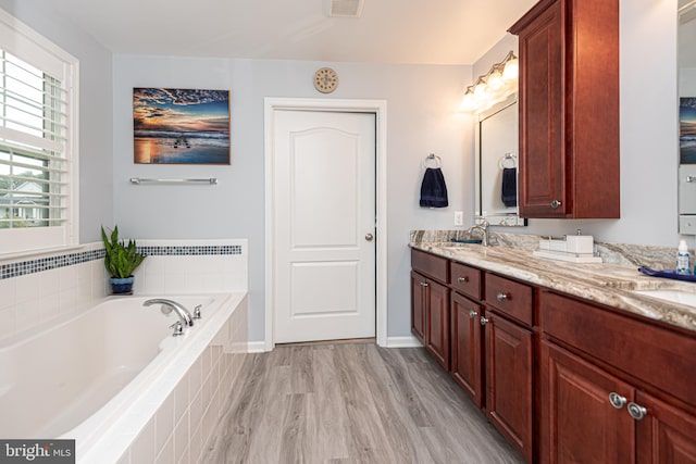 bathroom with vanity, hardwood / wood-style flooring, and a relaxing tiled tub