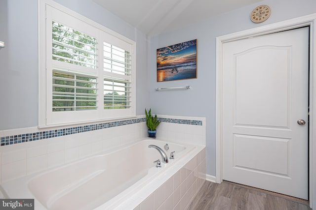 bathroom featuring hardwood / wood-style flooring and tiled tub