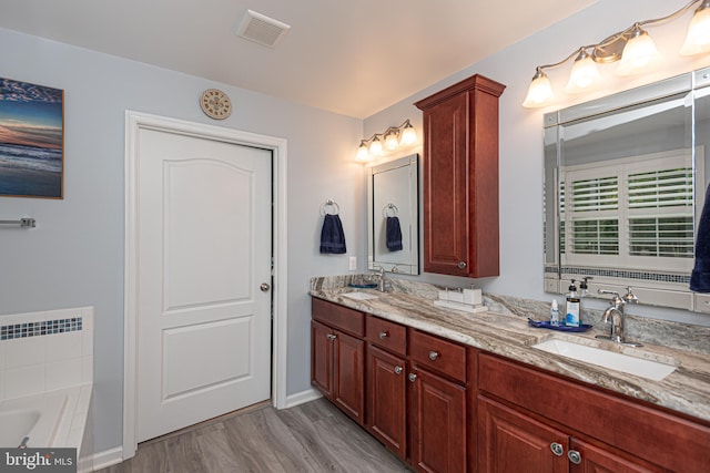 bathroom with hardwood / wood-style flooring, vanity, radiator, and a washtub