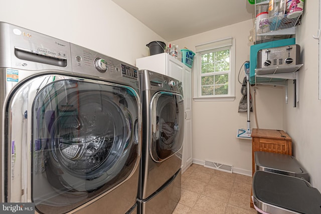 clothes washing area with cabinets and washer and clothes dryer