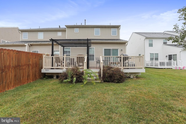 rear view of property with a deck, a pergola, and a yard