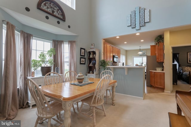 carpeted dining space featuring a towering ceiling and a healthy amount of sunlight