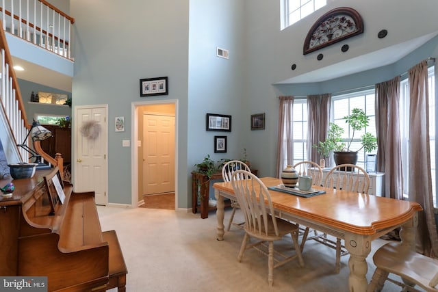 carpeted dining space with a towering ceiling