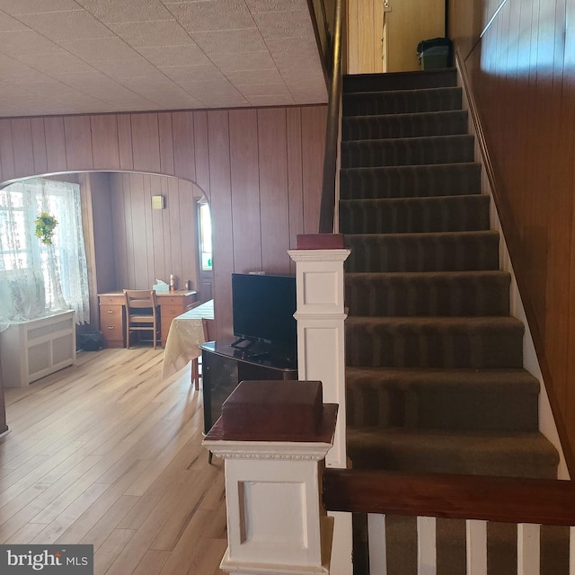 stairs featuring hardwood / wood-style floors and wooden walls