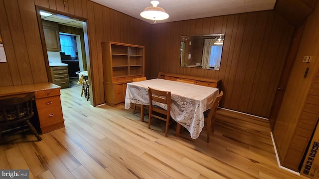 dining space with light hardwood / wood-style flooring and wooden walls