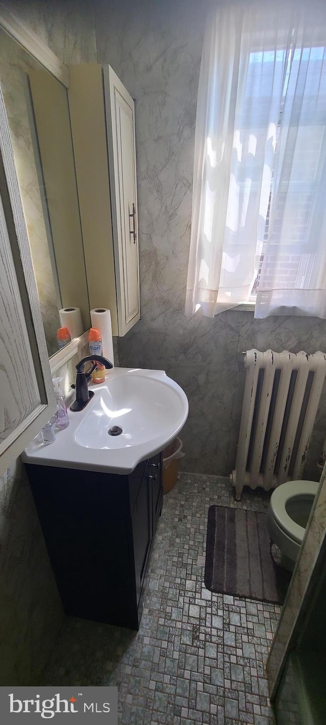 bathroom featuring vanity, radiator heating unit, and toilet