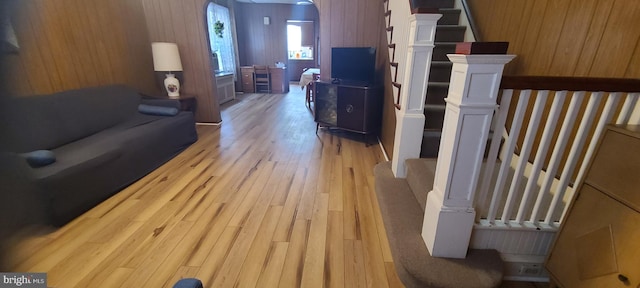 living room with light hardwood / wood-style flooring and wooden walls