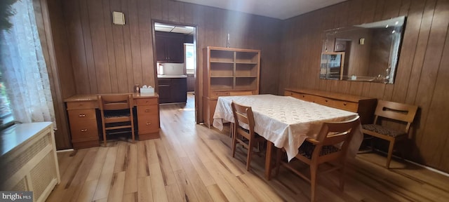 dining space featuring light wood-type flooring and wood walls