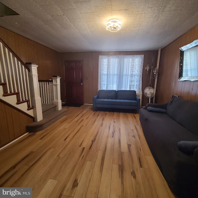 unfurnished living room featuring a textured ceiling, wooden walls, and light wood-type flooring