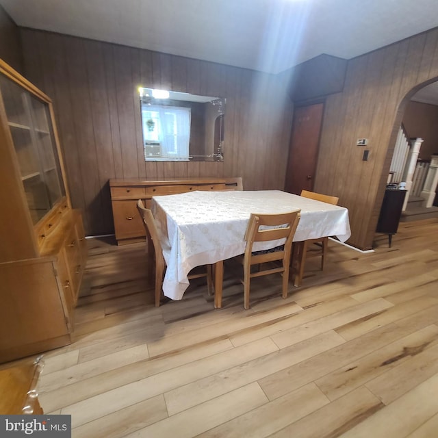 dining space with light hardwood / wood-style floors and wood walls