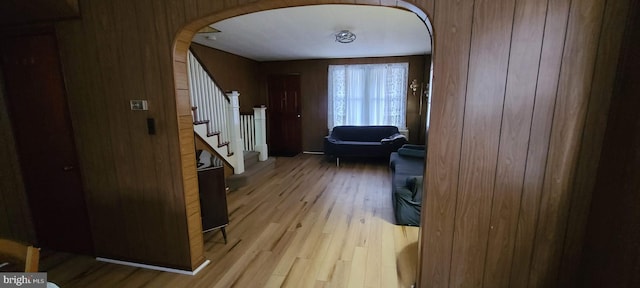 hall with wood walls and light hardwood / wood-style flooring