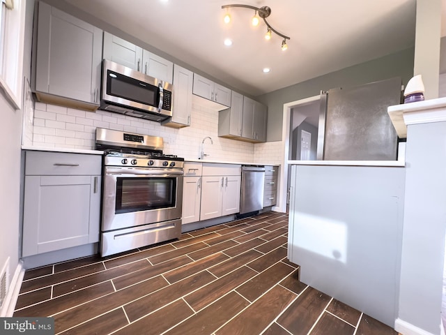 kitchen featuring backsplash, gray cabinetry, sink, and stainless steel appliances