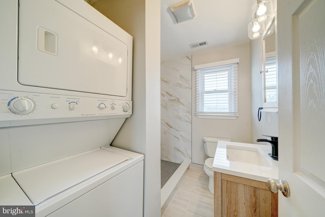 washroom with light wood-type flooring, stacked washer and clothes dryer, and sink