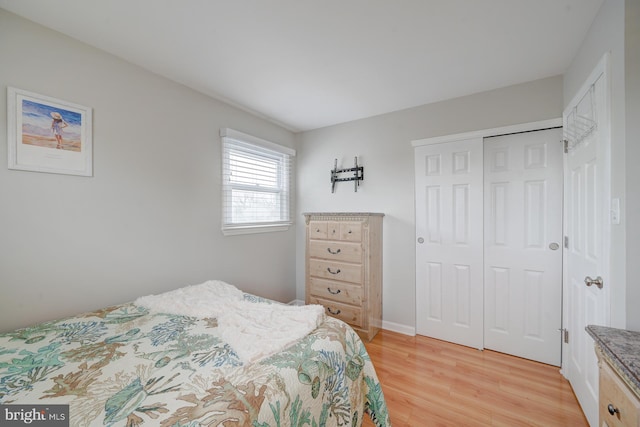 bedroom with light hardwood / wood-style floors and a closet