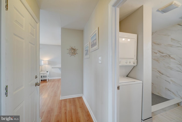 clothes washing area with light wood-type flooring and stacked washer and clothes dryer