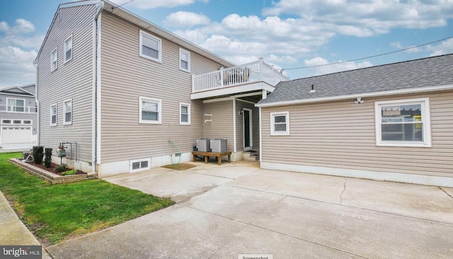 back of house with a balcony, a patio area, and a lawn