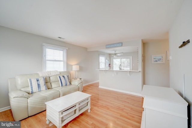 living room with light wood-type flooring, a wealth of natural light, and ceiling fan