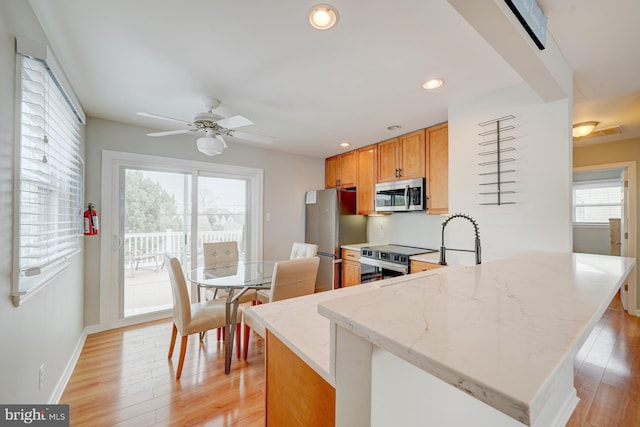 kitchen featuring a wealth of natural light, light wood-type flooring, and appliances with stainless steel finishes