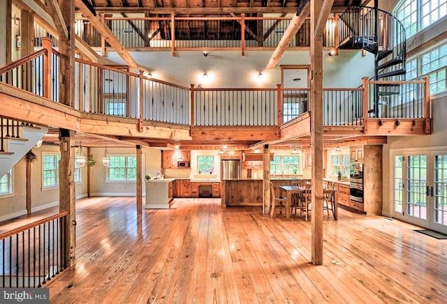 unfurnished living room featuring light wood-type flooring and a high ceiling