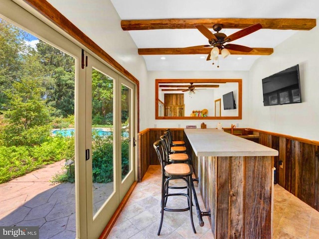 interior space featuring wood walls, vaulted ceiling with beams, a kitchen bar, and a kitchen island