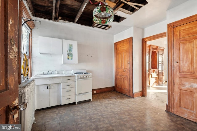 kitchen featuring white gas stove, white cabinetry, and sink