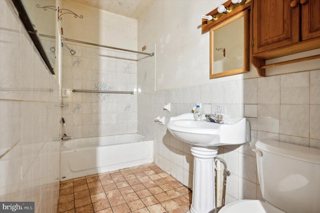 bathroom with tile walls, tiled shower / bath combo, and toilet