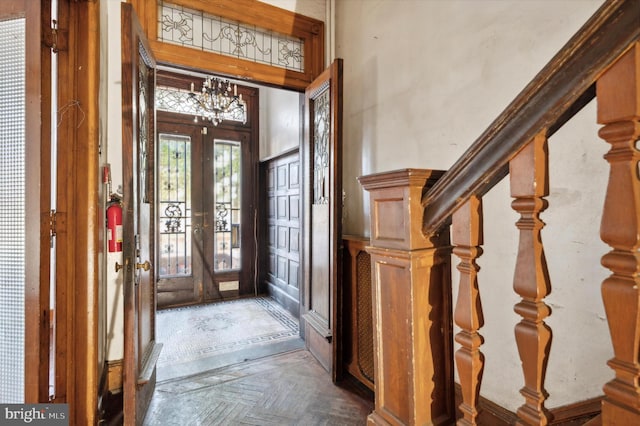 entryway with french doors, a notable chandelier, and parquet floors