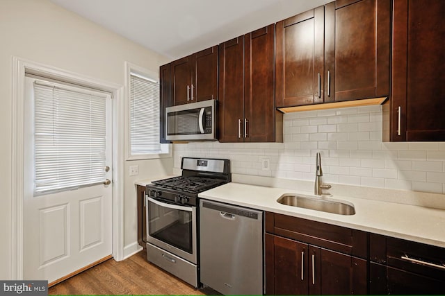 kitchen with tasteful backsplash, sink, hardwood / wood-style floors, and appliances with stainless steel finishes