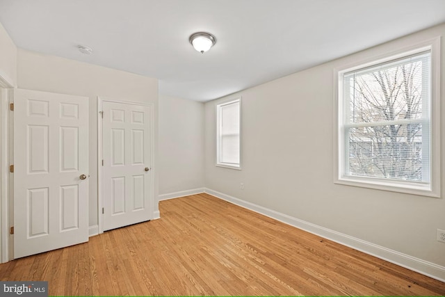 unfurnished bedroom with light wood-type flooring and multiple windows