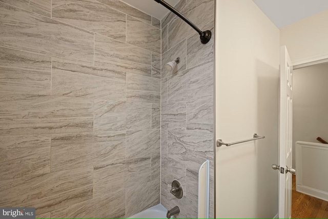 bathroom with tiled shower / bath combo and hardwood / wood-style flooring