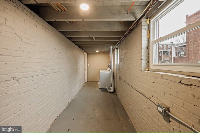 basement featuring washer / dryer and brick wall