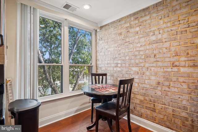 dining space with ornamental molding, brick wall, and dark hardwood / wood-style flooring