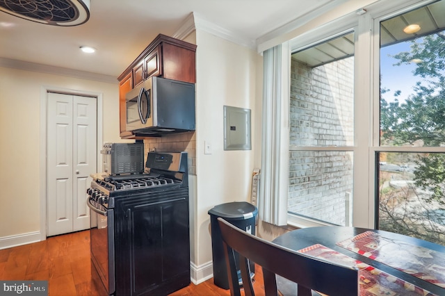 kitchen featuring ornamental molding, electric panel, dark wood-type flooring, and black gas range oven