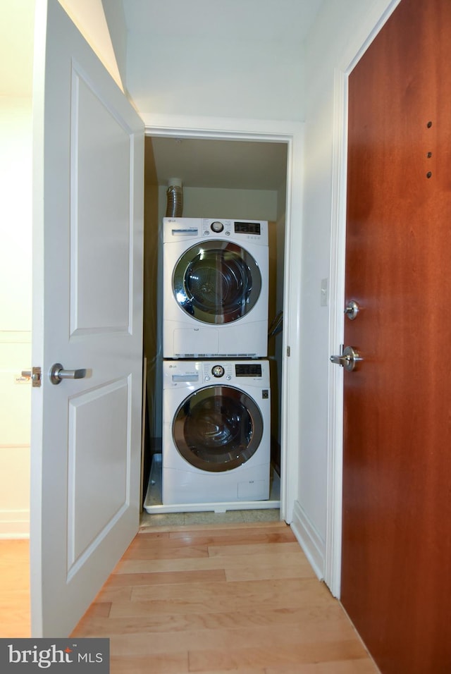 clothes washing area featuring light hardwood / wood-style floors and stacked washer and clothes dryer