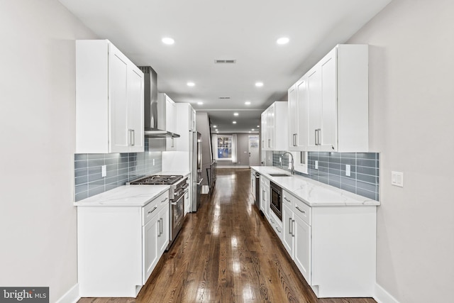 kitchen with wall chimney exhaust hood, appliances with stainless steel finishes, and white cabinets