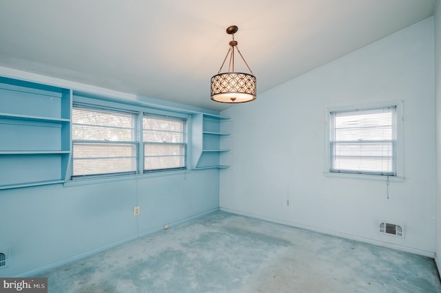 carpeted empty room featuring vaulted ceiling