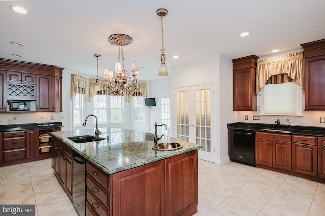 kitchen featuring dark stone counters, black appliances, a center island with sink, sink, and a notable chandelier