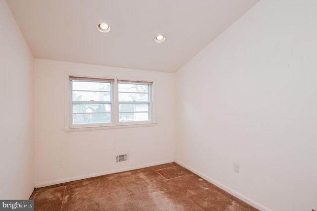 carpeted spare room featuring lofted ceiling